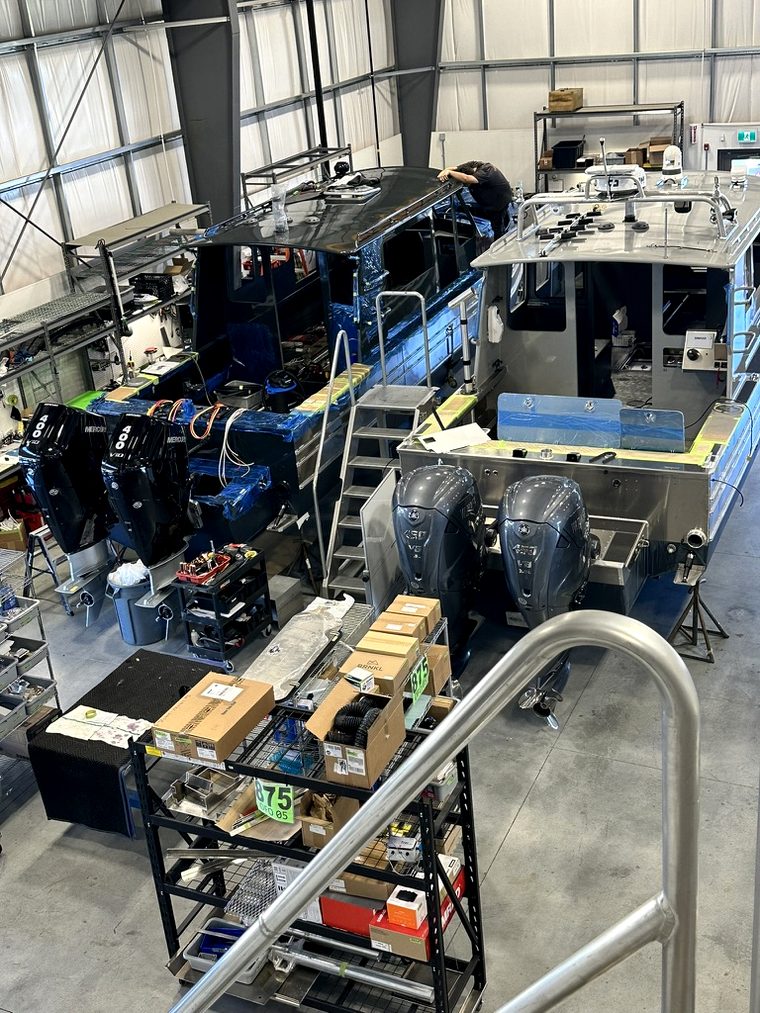 Two boats being built side by side on a manufacturing shop floor